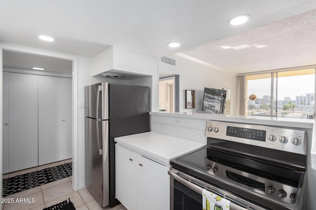 kitchen featuring stainless steel appliances, light tile patterned floors, a textured ceiling, and white cabinets