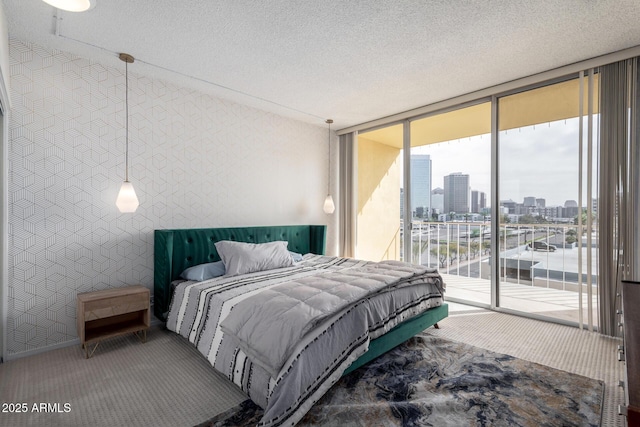 bedroom featuring access to exterior, carpet floors, a textured ceiling, and a wall of windows