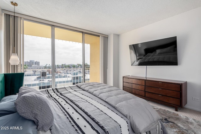 carpeted bedroom featuring floor to ceiling windows and a textured ceiling