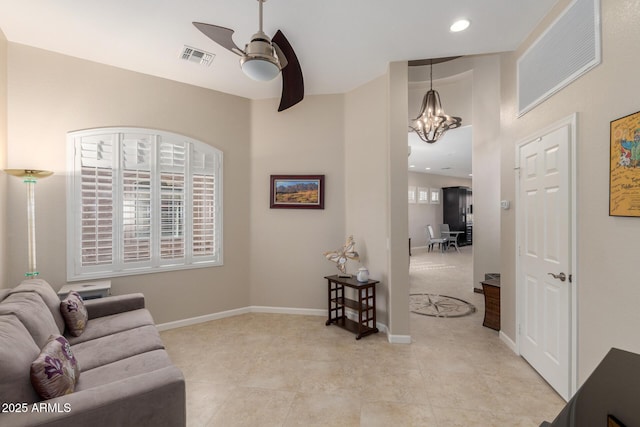 living room with light tile patterned floors and ceiling fan with notable chandelier