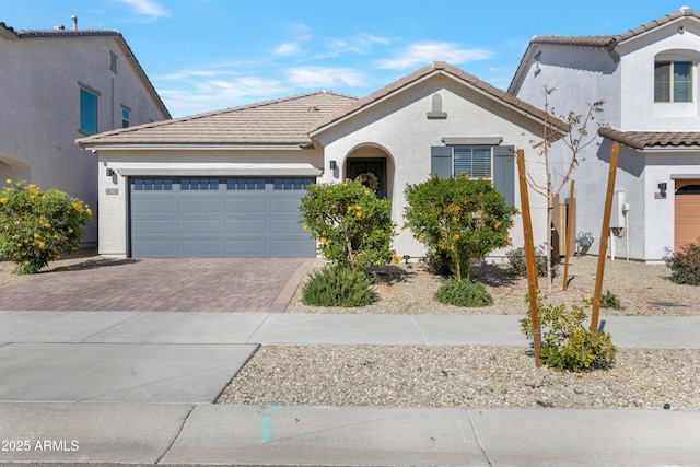 view of front of house with a garage, a tiled roof, decorative driveway, and stucco siding