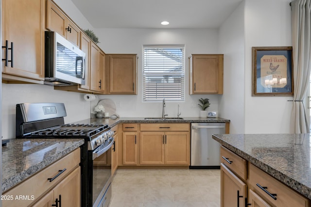 kitchen with light tile patterned flooring, recessed lighting, stainless steel appliances, a sink, and dark stone counters