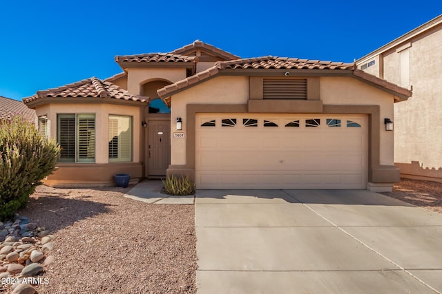 mediterranean / spanish-style home featuring a tile roof, an attached garage, driveway, and stucco siding