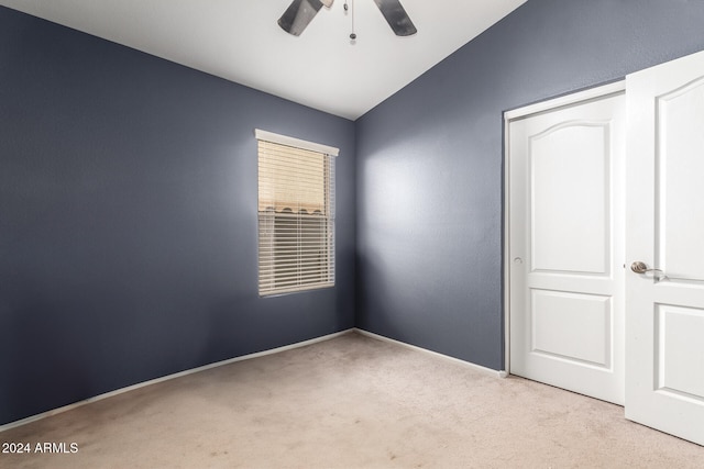 unfurnished bedroom featuring ceiling fan, vaulted ceiling, light carpet, and a closet