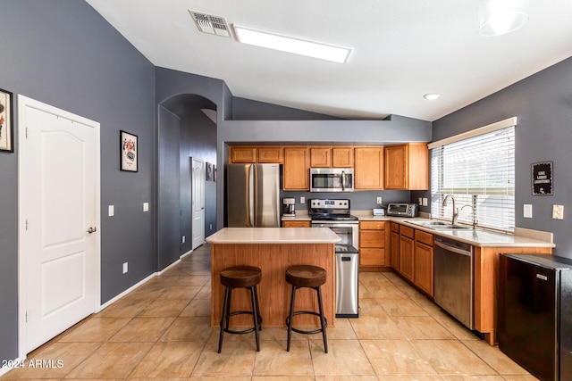 kitchen with stainless steel appliances, a kitchen island, lofted ceiling, and sink