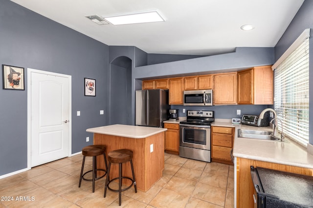 kitchen with a kitchen breakfast bar, stainless steel appliances, vaulted ceiling, sink, and a kitchen island