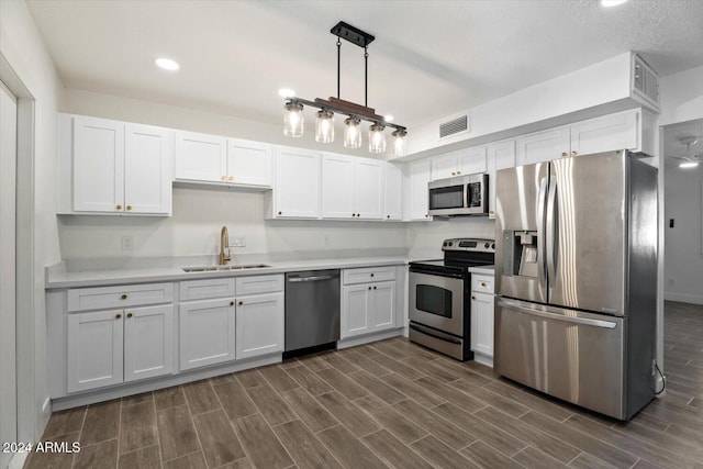 kitchen with white cabinets, appliances with stainless steel finishes, dark hardwood / wood-style flooring, and sink