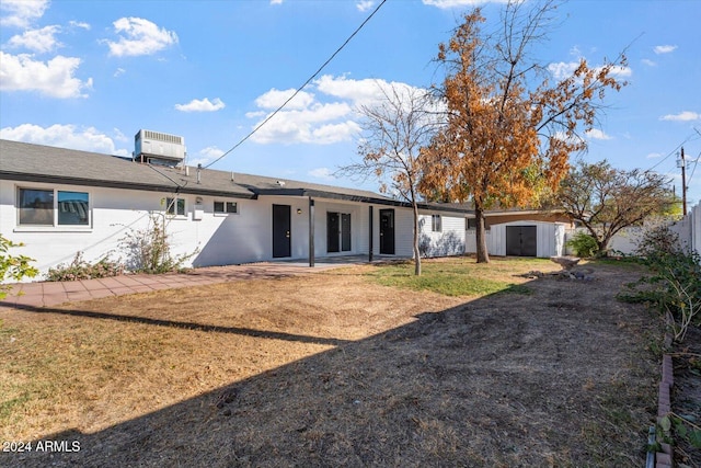 view of front of property featuring cooling unit, a front yard, and a storage unit