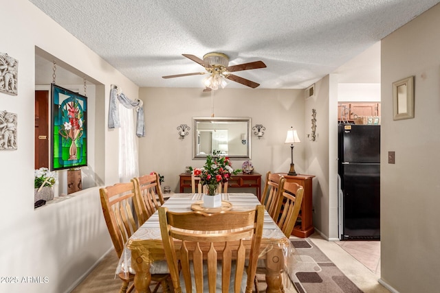 dining room featuring ceiling fan, light colored carpet, and a textured ceiling