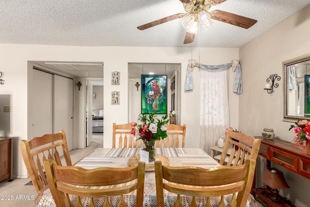 carpeted dining space with ceiling fan and a textured ceiling