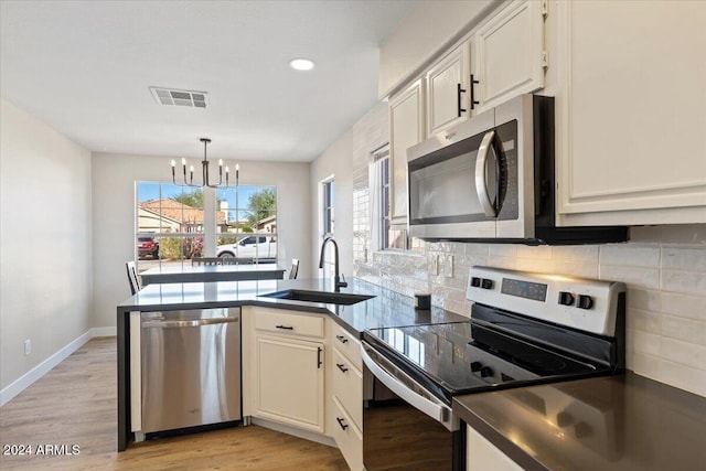 kitchen with stainless steel appliances, sink, light hardwood / wood-style flooring, and an inviting chandelier