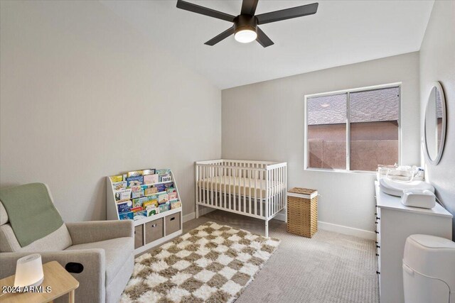 bedroom with sink, light carpet, ceiling fan, a crib, and vaulted ceiling