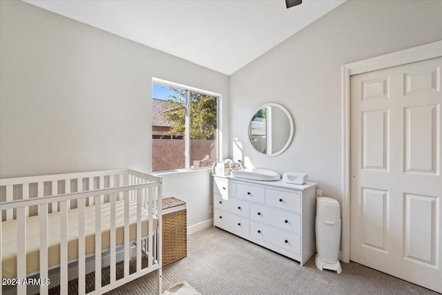 carpeted bedroom featuring lofted ceiling and a nursery area