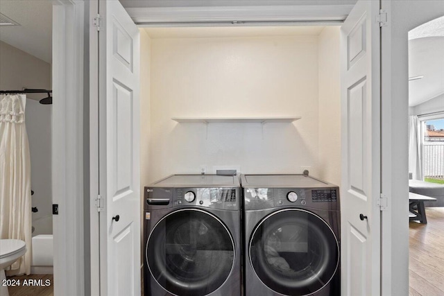 laundry room with wood-type flooring and separate washer and dryer