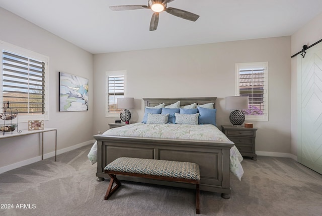 bedroom featuring a barn door, light colored carpet, multiple windows, and ceiling fan