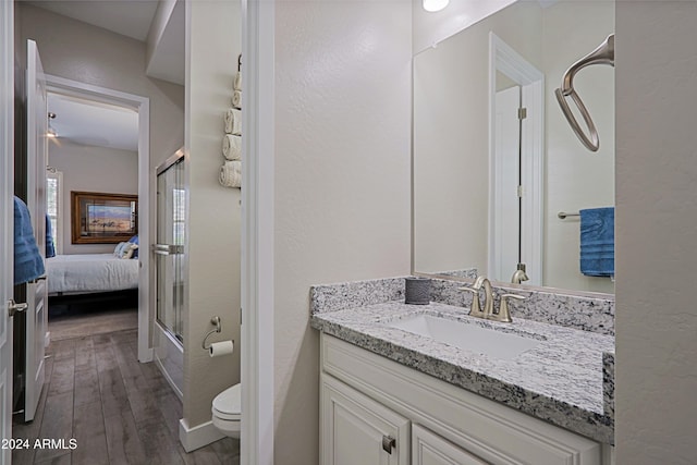 full bathroom with hardwood / wood-style floors, vanity, toilet, and bath / shower combo with glass door