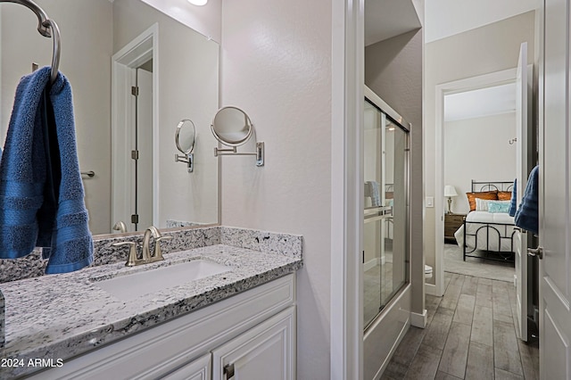 bathroom featuring wood-type flooring, vanity, and enclosed tub / shower combo