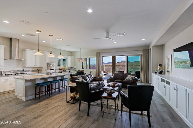 living room with light hardwood / wood-style flooring, ceiling fan, and sink