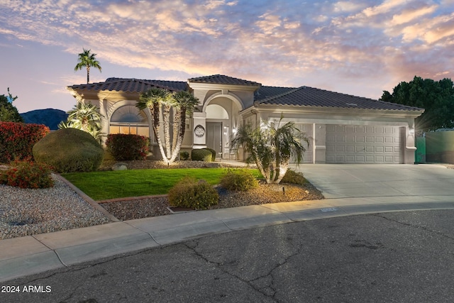 mediterranean / spanish-style home featuring a lawn and a garage