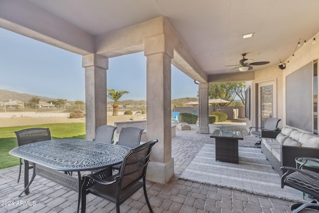 view of patio with ceiling fan, a mountain view, and an outdoor living space with a fire pit