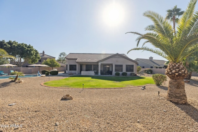 rear view of house with a lawn and a fenced in pool