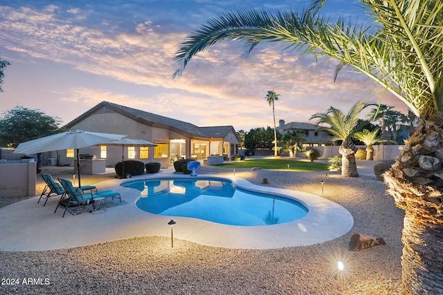 pool at dusk featuring a patio