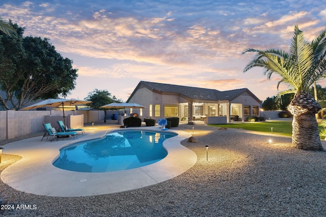 pool at dusk featuring a patio