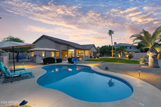 pool at dusk featuring a patio