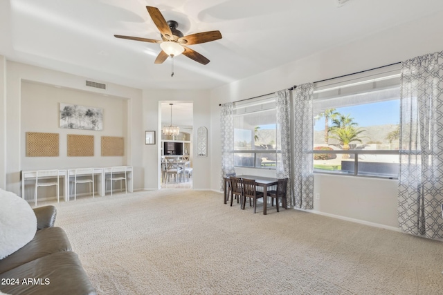 carpeted living room featuring ceiling fan with notable chandelier