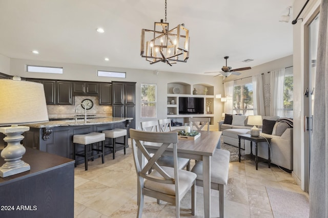 dining space featuring ceiling fan with notable chandelier and sink