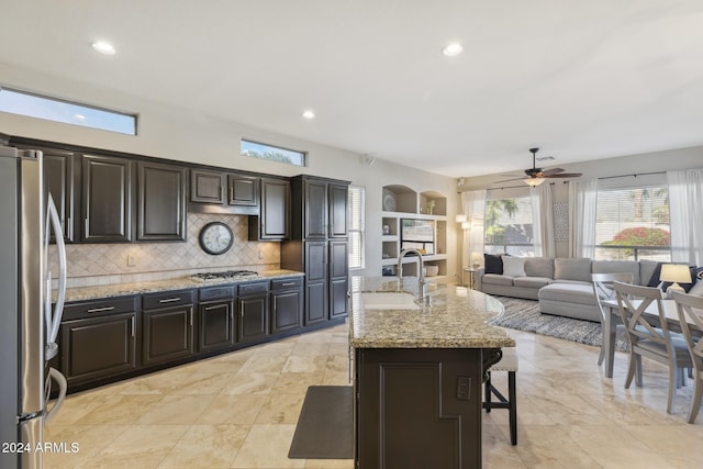 kitchen featuring decorative backsplash, appliances with stainless steel finishes, sink, a center island with sink, and a breakfast bar area