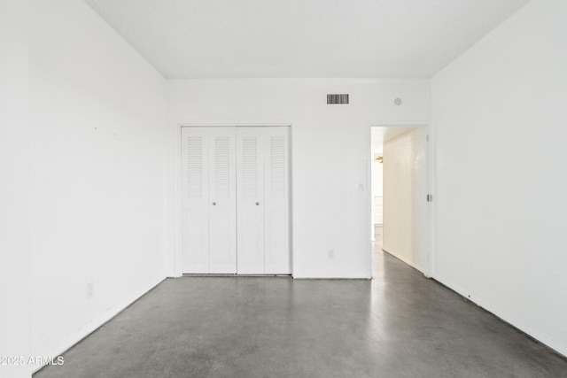 unfurnished bedroom with a closet, visible vents, and concrete flooring