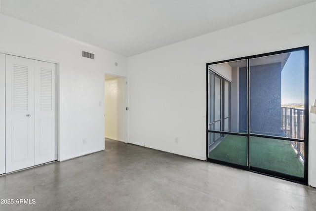 spare room featuring baseboards, visible vents, and concrete floors