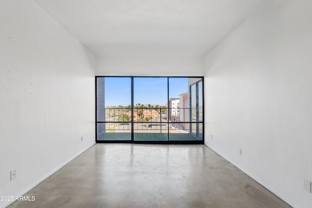 unfurnished room featuring baseboards and finished concrete floors