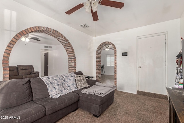 carpeted living area featuring ceiling fan, visible vents, and arched walkways