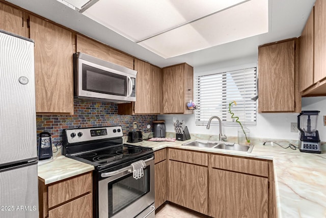 kitchen featuring stainless steel appliances, light countertops, a sink, and tasteful backsplash