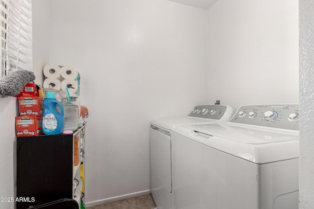 clothes washing area featuring laundry area, tile patterned flooring, washing machine and clothes dryer, and baseboards