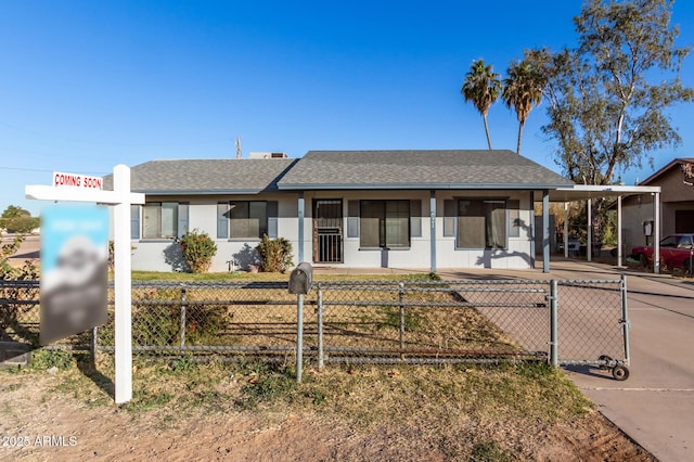 ranch-style house featuring concrete driveway, an attached carport, a fenced front yard, and roof with shingles