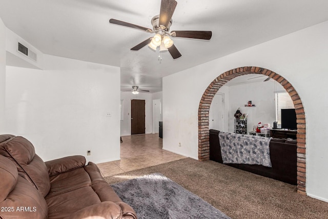 carpeted living area featuring visible vents, ceiling fan, baseboards, and tile patterned floors