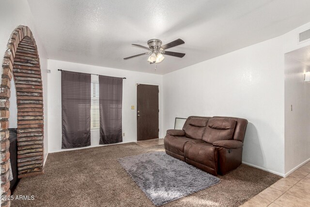 living area with light carpet, ceiling fan, a textured ceiling, and light tile patterned flooring