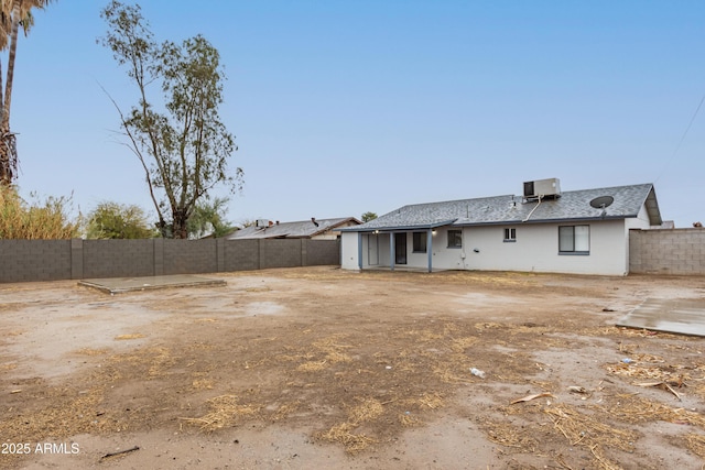 back of property with central AC unit and a fenced backyard