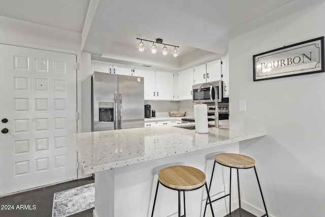 kitchen with white cabinetry, sink, stainless steel appliances, light stone counters, and dark tile patterned flooring