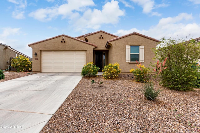 mediterranean / spanish home featuring an attached garage, concrete driveway, a tiled roof, and stucco siding