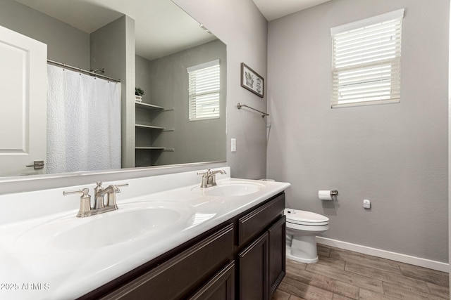 bathroom featuring toilet, wood finished floors, baseboards, and double vanity