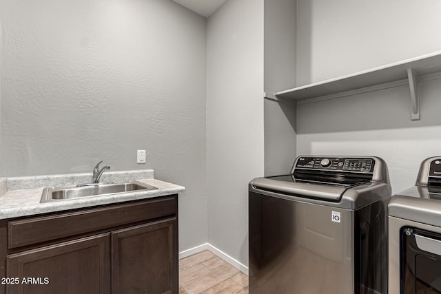 laundry room featuring washer and clothes dryer, light wood-type flooring, cabinet space, and baseboards