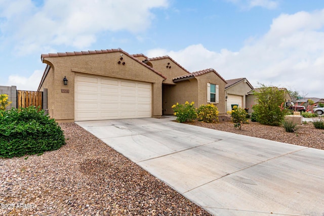 mediterranean / spanish-style house with concrete driveway, stucco siding, a tile roof, a garage, and fence