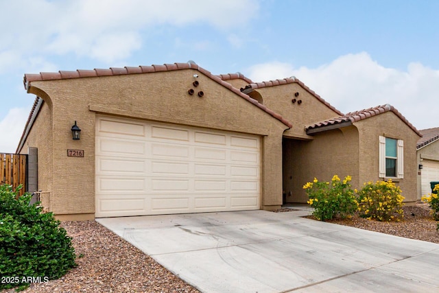 mediterranean / spanish home featuring concrete driveway, a garage, a tiled roof, stucco siding, and fence