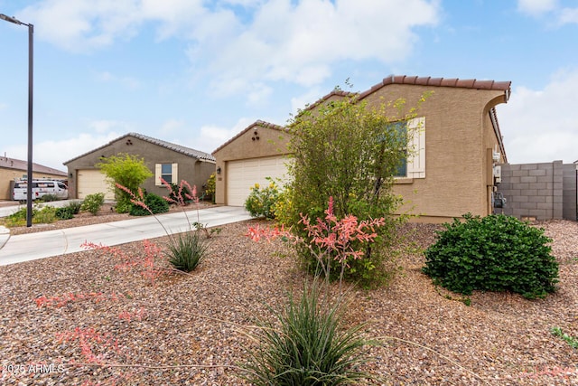 mediterranean / spanish-style home featuring stucco siding, a garage, concrete driveway, and a tile roof