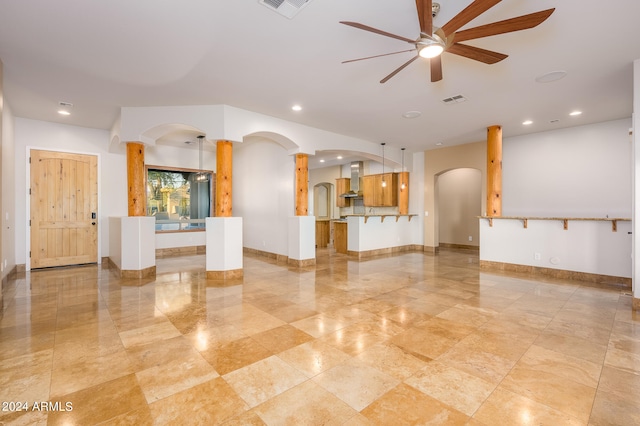 unfurnished living room featuring ceiling fan and ornate columns