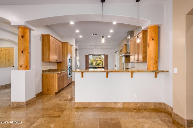 kitchen with hanging light fixtures, kitchen peninsula, tasteful backsplash, wall chimney exhaust hood, and oven